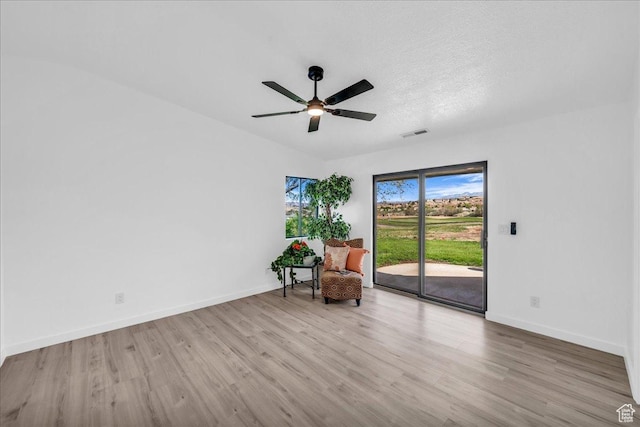 unfurnished room featuring baseboards, a textured ceiling, a ceiling fan, visible vents, and wood finished floors