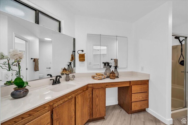 bathroom with vanity, a stall shower, and wood finished floors