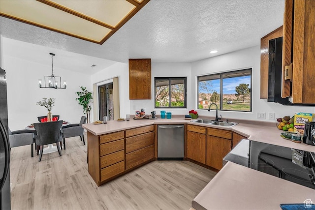 kitchen featuring a sink, light countertops, a peninsula, brown cabinets, and stainless steel dishwasher