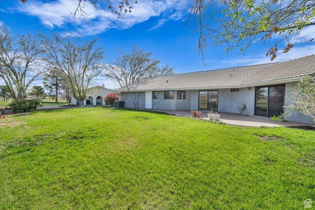 back of property featuring a yard, a tiled roof, cooling unit, a patio, and stucco siding