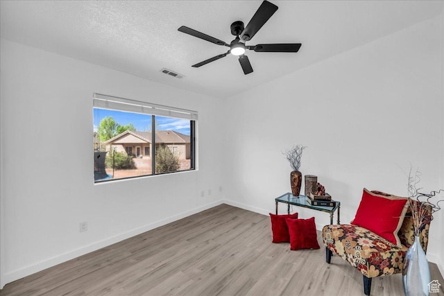 sitting room featuring visible vents, baseboards, ceiling fan, a textured ceiling, and wood finished floors