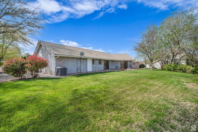 back of property featuring central AC, a tile roof, a lawn, and stucco siding