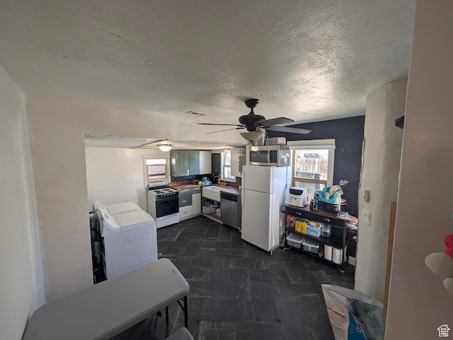 kitchen with washer / dryer, a sink, a ceiling fan, and appliances with stainless steel finishes