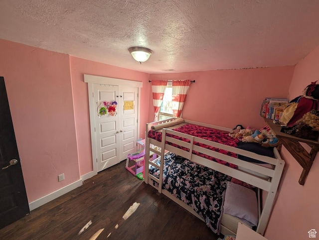 bedroom featuring baseboards, wood finished floors, and a textured ceiling