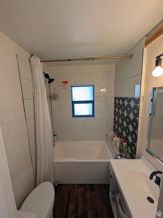 bathroom featuring toilet, shower / bathtub combination with curtain, vanity, and wood finished floors