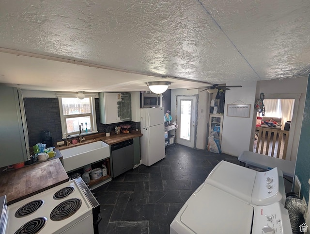 kitchen with stone finish floor, a textured ceiling, a sink, and appliances with stainless steel finishes