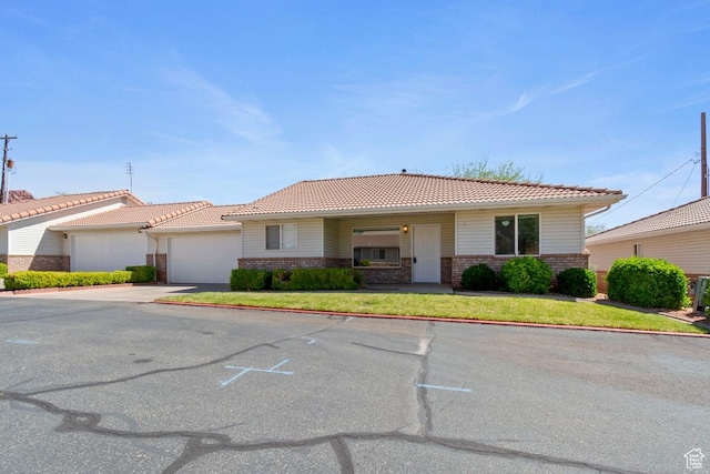 single story home with concrete driveway, brick siding, an attached garage, and a tile roof