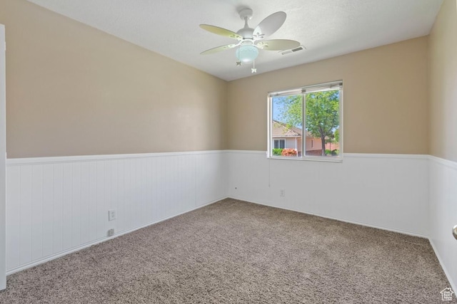 empty room with visible vents, a wainscoted wall, and carpet floors