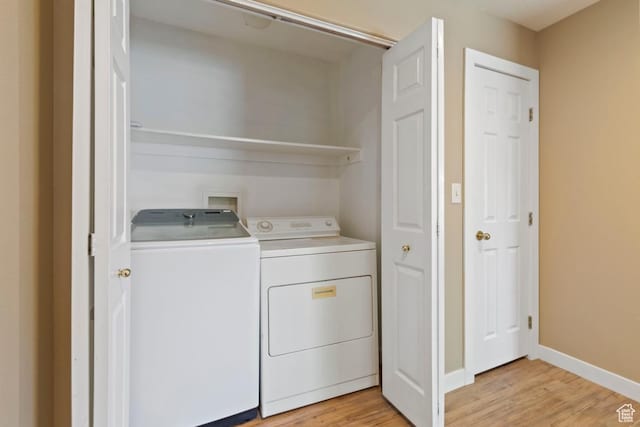 washroom with light wood finished floors, laundry area, washing machine and clothes dryer, and baseboards
