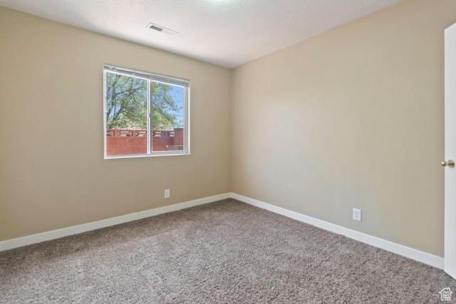 carpeted spare room featuring baseboards and visible vents