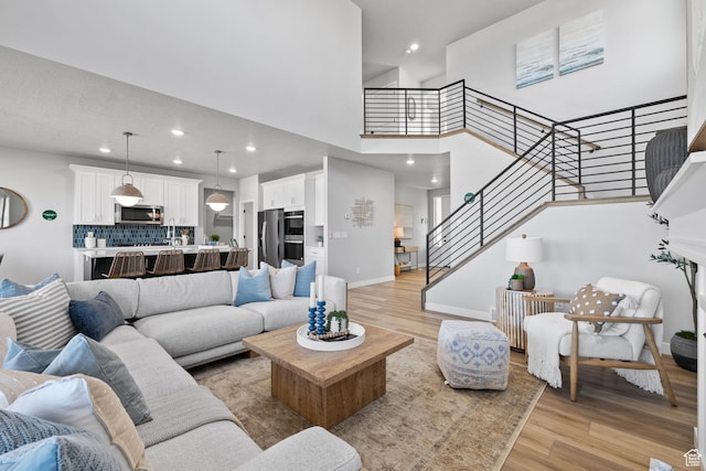 199 N Mia Cv E Unit 12, Saratoga Springs, UT 84045 - living room with light wood-style floors, stairs, a high ceiling, recessed lighting, and baseboards