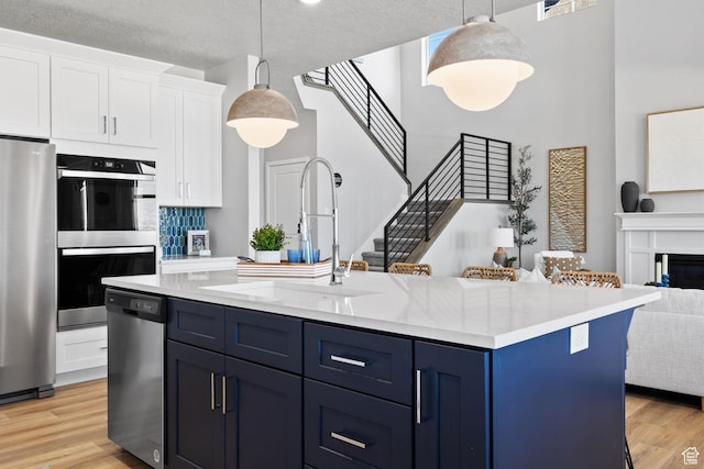 199 N Mia Cv E Unit 12, Saratoga Springs, UT 84045 - kitchen with appliances with stainless steel finishes, a towering ceiling, blue cabinetry, open floor plan, and a sink