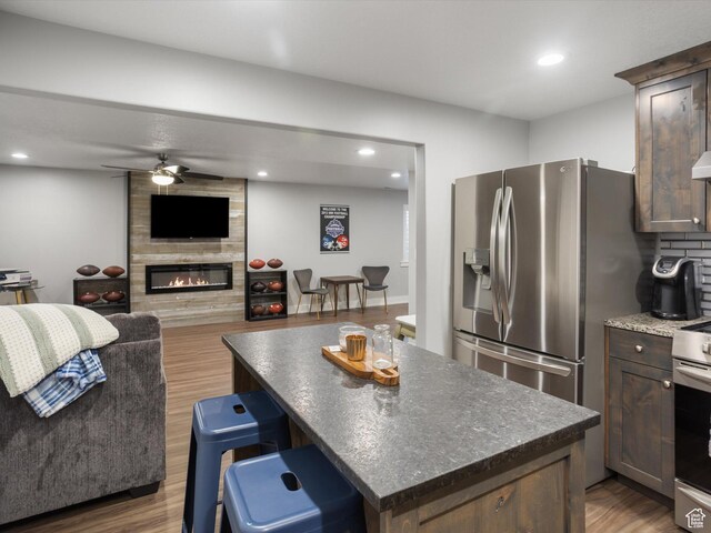 131 Crockett Ave, Logan, UT 84321 - kitchen with a ceiling fan, stainless steel appliances, a center island, wood finished floors, and a fireplace