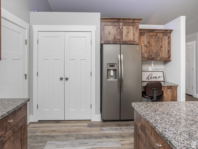 131 Crockett Ave, Logan, UT 84321 - kitchen featuring stainless steel fridge with ice dispenser, light stone counters, light wood-type flooring, and decorative backsplash