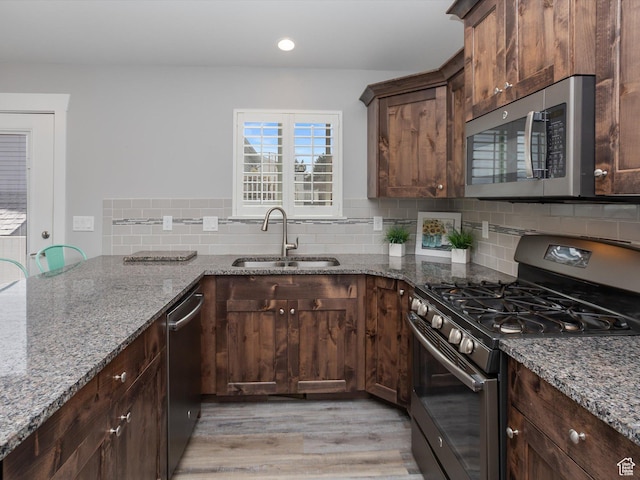 131 Crockett Ave, Logan, UT 84321 - kitchen with appliances with stainless steel finishes, a sink, light wood-type flooring, stone counters, and decorative backsplash