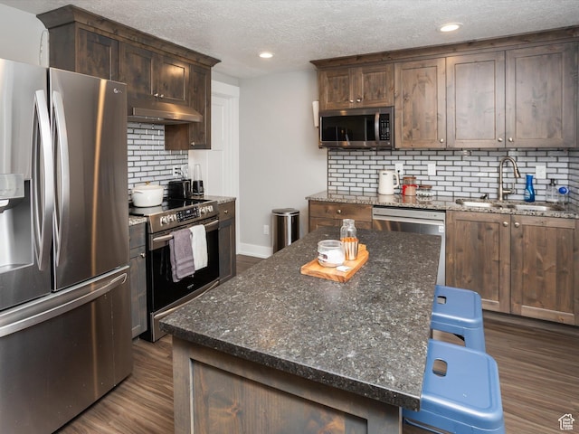 131 Crockett Ave, Logan, UT 84321 - kitchen with appliances with stainless steel finishes, under cabinet range hood, a sink, dark wood-style flooring, and backsplash