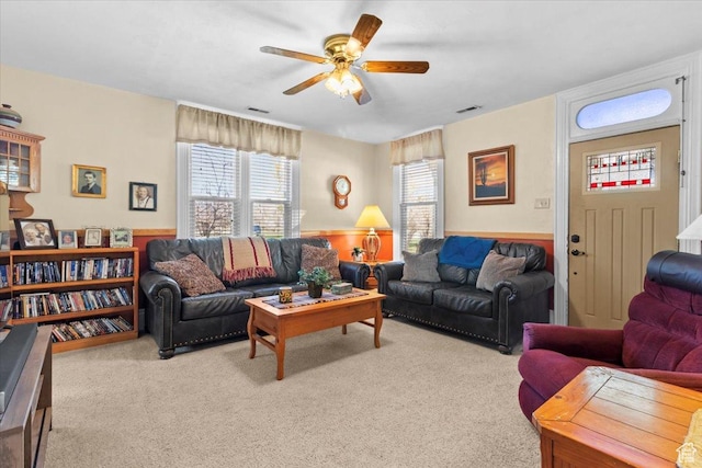 living area featuring visible vents, ceiling fan, and light colored carpet