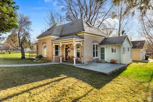 back of house with brick siding, a yard, and a patio area