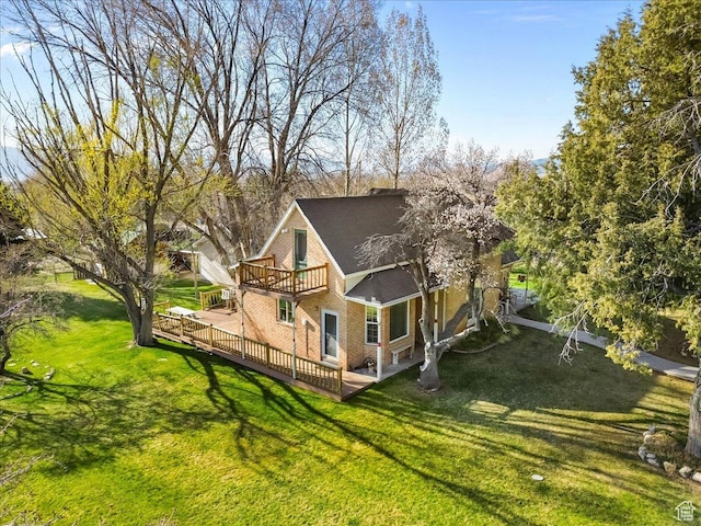 view of side of property with brick siding, a yard, a deck, and roof with shingles