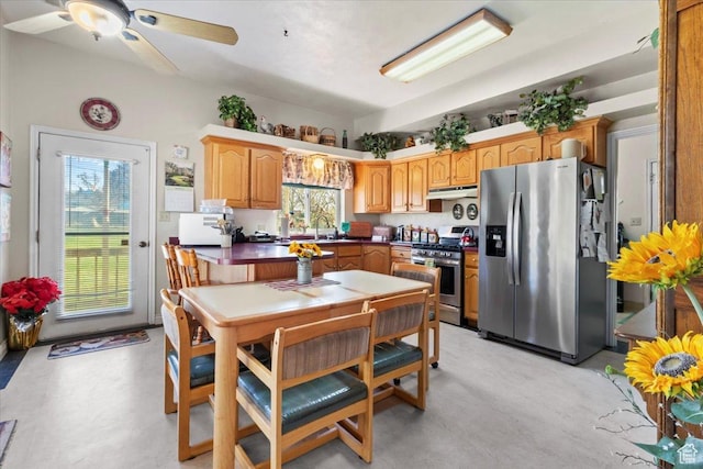 kitchen with ceiling fan, under cabinet range hood, dark countertops, a sink, and stainless steel appliances