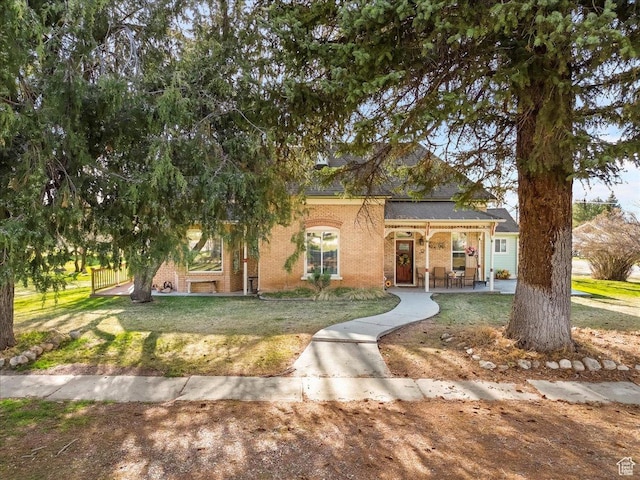 view of front facade featuring brick siding, a front lawn, and covered porch
