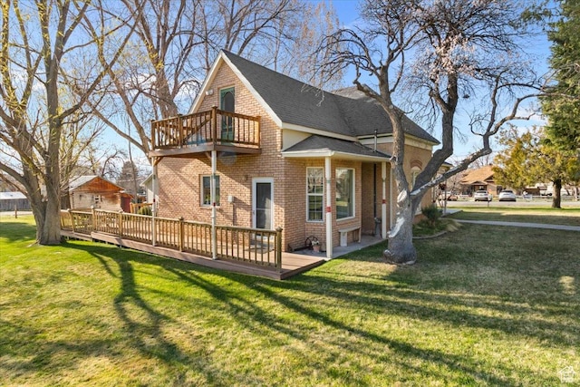 rear view of house featuring a balcony, a lawn, brick siding, a wooden deck, and a shingled roof