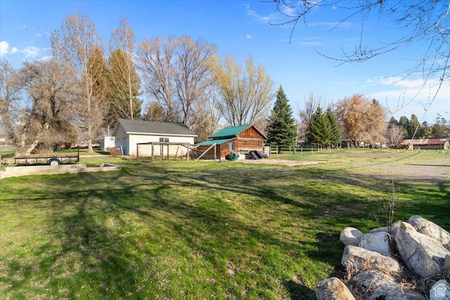 view of yard with a barn, fence, and an outdoor structure