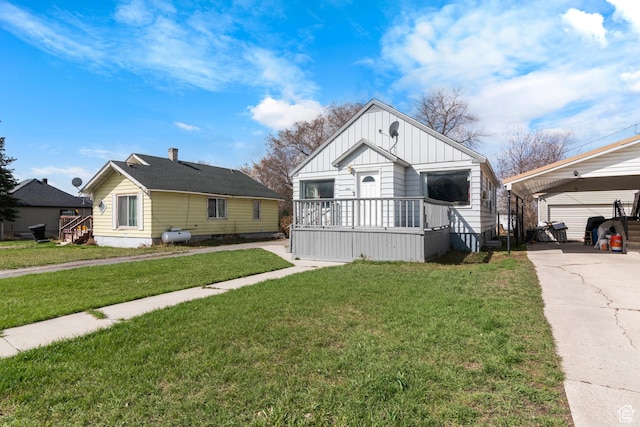 268 S Main St, Malad City, ID 83252 - bungalow-style home with a front yard, a carport, board and batten siding, concrete driveway, and an outbuilding