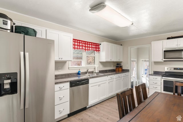 268 S Main St, Malad City, ID 83252 - kitchen featuring light wood-style flooring, white cabinetry, dark countertops, stainless steel appliances, and a sink