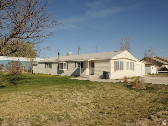 rear view of property featuring entry steps, an attached garage, a yard, and driveway