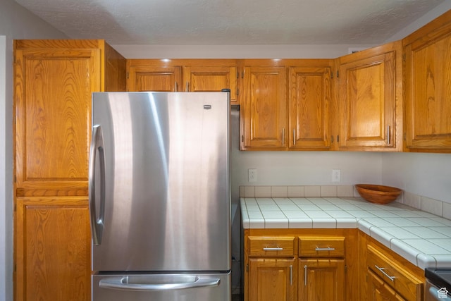 kitchen featuring brown cabinets, freestanding refrigerator, and range with electric cooktop