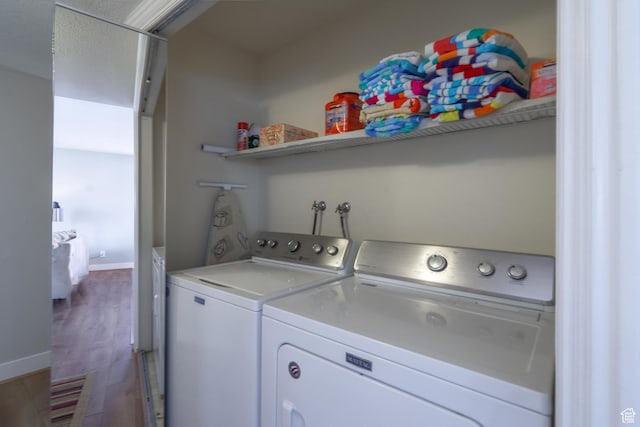 laundry room with baseboards, wood finished floors, and washer and dryer