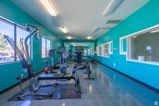 gym featuring baseboards, visible vents, and a textured ceiling