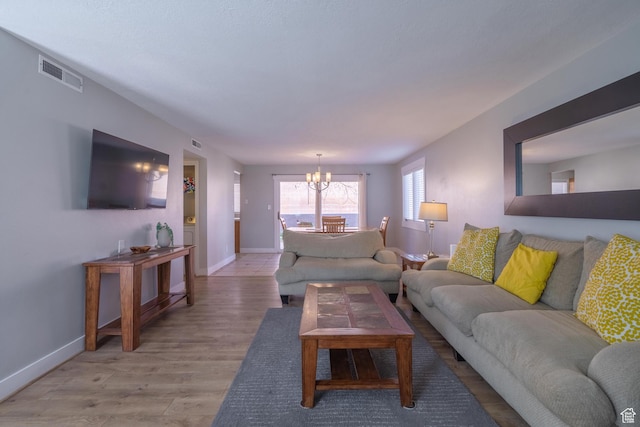 living area with baseboards, a chandelier, visible vents, and light wood-type flooring