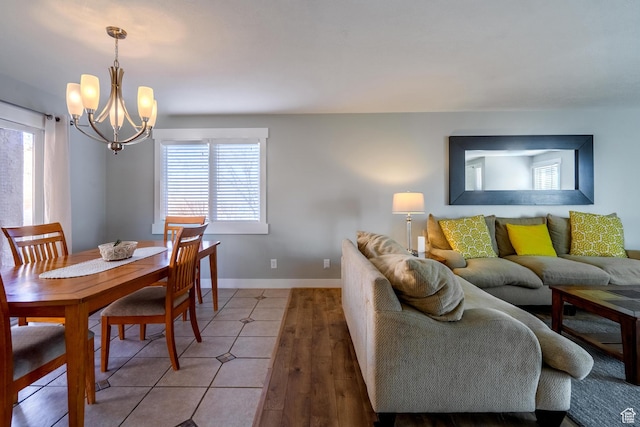 dining area featuring a wealth of natural light, light wood finished floors, baseboards, and a notable chandelier