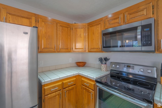 kitchen featuring brown cabinetry and appliances with stainless steel finishes