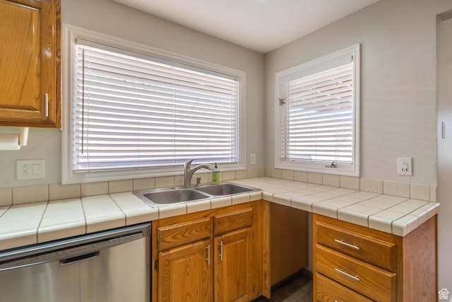 kitchen with light countertops, dishwasher, brown cabinetry, and a sink