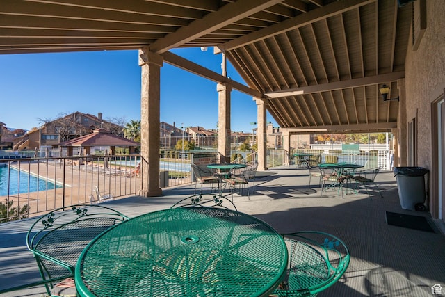 view of patio featuring fence, outdoor dining area, a community pool, and a residential view