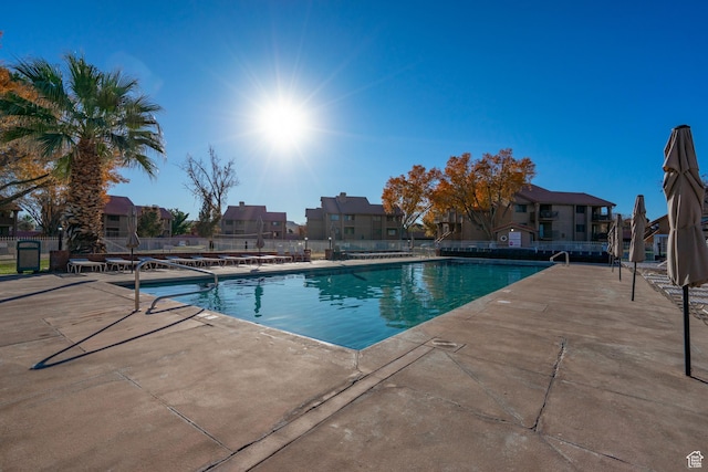 pool with fence, a patio area, and a residential view
