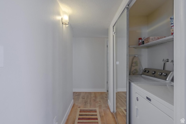 laundry room with laundry area, baseboards, separate washer and dryer, light wood-style flooring, and a textured ceiling