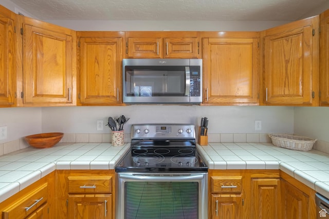 kitchen featuring brown cabinetry, appliances with stainless steel finishes, and light countertops