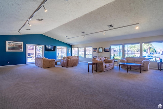 carpeted living room featuring lofted ceiling, rail lighting, visible vents, baseboards, and a textured ceiling
