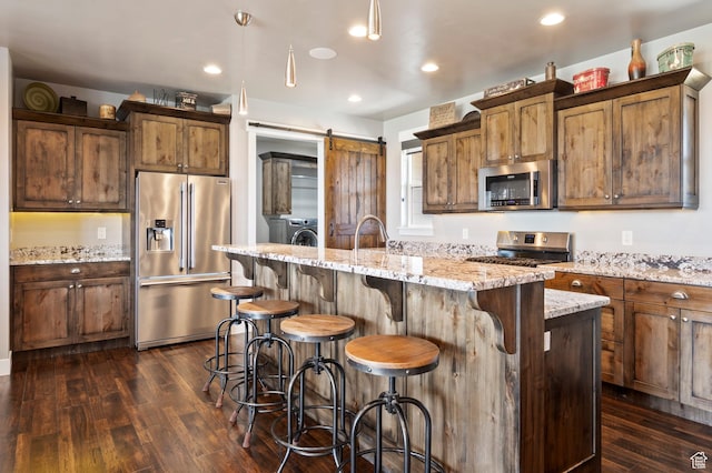 5185 N 600 E, Enoch, UT 84721 - kitchen featuring dark wood finished floors, a center island with sink, a kitchen breakfast bar, and appliances with stainless steel finishes