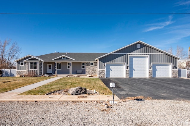 ranch-style home with board and batten siding, stone siding, a front lawn, a garage, and covered porch