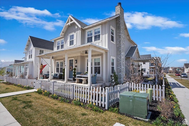 view of front facade featuring a patio area, a chimney, board and batten siding, a residential view, and fence private yard