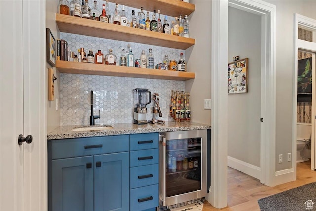 bar with light wood-type flooring, a dry bar, a sink, wine cooler, and backsplash