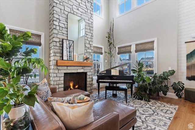 living area with a high ceiling, wood finished floors, a fireplace, and baseboards