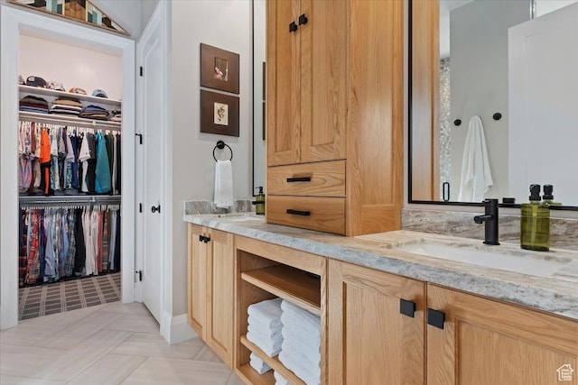 bathroom featuring a sink, a spacious closet, and double vanity