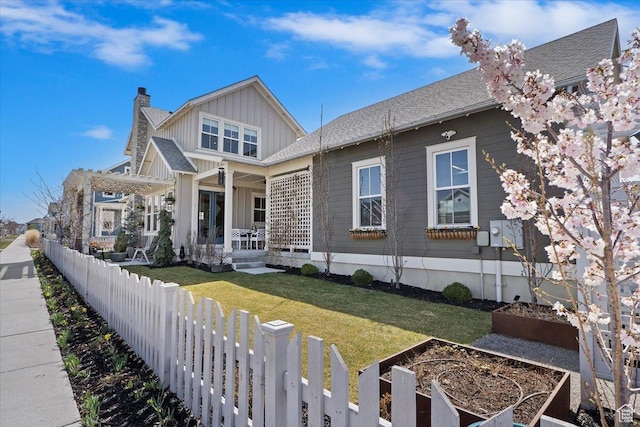 view of front facade featuring board and batten siding, covered porch, fence private yard, a garden, and a chimney