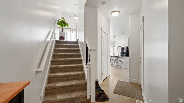 staircase featuring wood finished floors and a ceiling fan